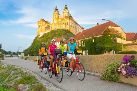 Cyclists along the bike path with a view of Melk Abbey