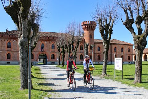 Two cyclists in front of a castle in Pollenzo